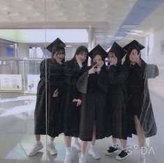 four young women in graduation gowns taking a selfie