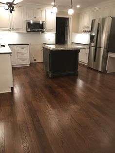 an empty kitchen with white cabinets and wood floors