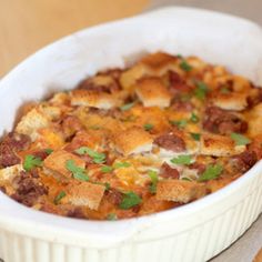 a casserole dish with meat and cheese in a white bowl on a wooden table