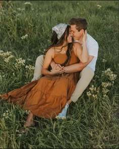 a man and woman are sitting in the grass with their noses close to each other