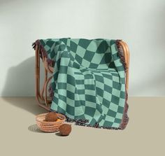 a green and white blanket sitting on top of a chair next to a basket filled with nuts