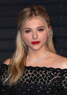 a woman with long blonde hair wearing a black dress and red lipstick is posing for the camera