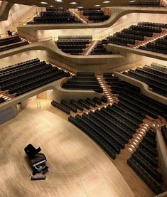 an empty auditorium with rows of seats and a piano on the floor in front of it