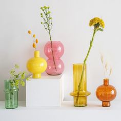 three different colored vases sitting on top of a white shelf next to each other