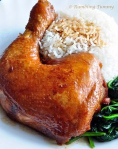 a white plate topped with rice and meat covered in sauce on top of spinach