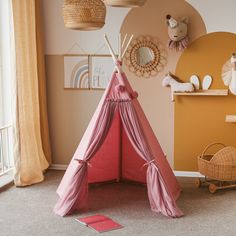 a pink teepee tent sitting in a child's room next to a teddy bear