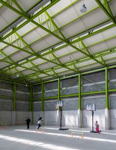 people are playing basketball in an empty building with green and white paint on the walls