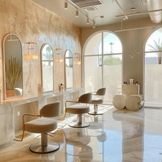 a salon with chairs and mirrors on the wall next to each other in front of large windows