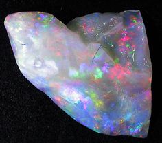 an opalite with white and pink colors on the inside, sitting on a black surface