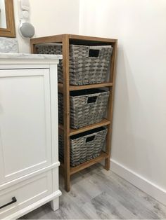 three baskets are stacked on top of a wooden shelf next to a white cabinet and mirror