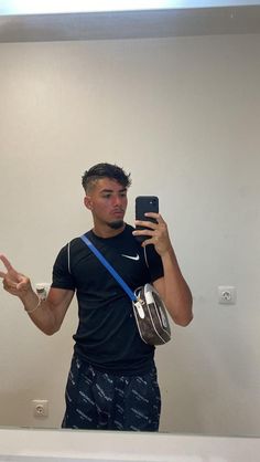 a man taking a selfie in front of a mirror with his cell phone and headphones