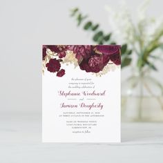 the burgundy and gold floral wedding card is displayed in front of a vase with flowers