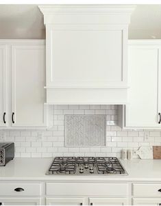 a kitchen with white cupboards and an oven in the middle of the countertop