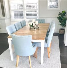 a dining room table with blue chairs and a white rug on the floor in front of it