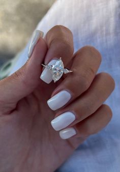 a woman's hand with white manies and a ring on her finger, holding a diamond