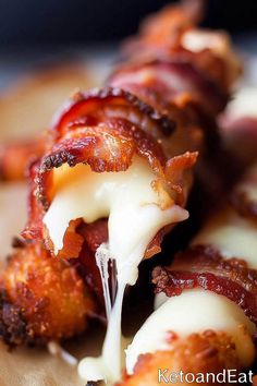 bacon wrapped in melted cheese on a cutting board