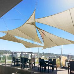 an outdoor dining area with tables and chairs under shade sails on a sunny day in the city