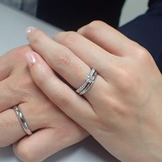 two hands holding each other with wedding rings on their fingers and engagement bands around them