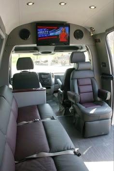 the interior of a vehicle with two seats and a television on the wall above it