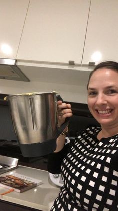 a woman is smiling while holding a pot