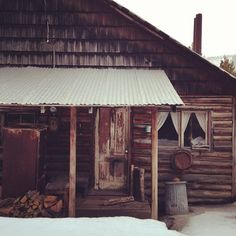 an old log cabin with snow on the ground