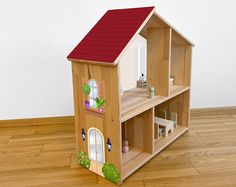 a wooden doll house with red roof and windows on the front, sitting on top of a hard wood floor