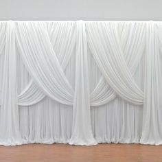 an empty room with white drapes on the wall