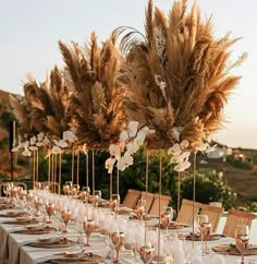 a long table is set with place settings and tall centerpieces for the tables