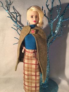 a barbie doll is standing next to a tree