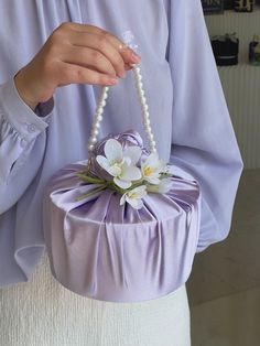 a woman is holding a purple purse with flowers on the handle and pearls hanging from it