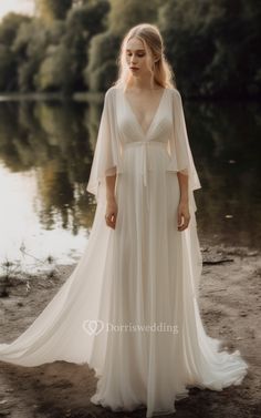 a woman in a white dress standing by the water