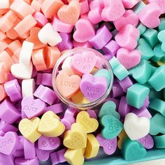 colorful candy hearts with the word love written on them are in a glass bowl and surrounded by other candies