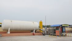 a large white tank sitting on top of a parking lot next to a gas station