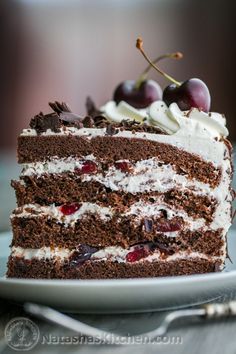 a piece of chocolate cake with white frosting and cherries