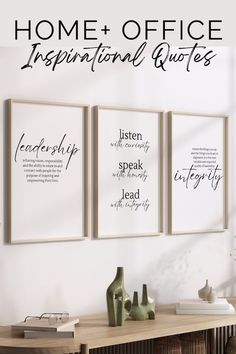 three framed posters on the wall above a wooden table with vases and other items