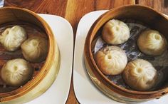 two bowls filled with dumplings sitting next to each other on top of a wooden table