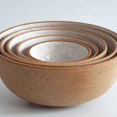 five brown and white bowls stacked on top of each other in front of a white background