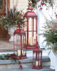 two red lanterns sitting on top of a step next to christmas wreaths and greenery