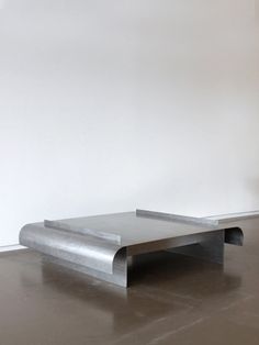 a metal table sitting on top of a hard wood floor next to a white wall