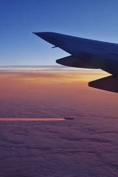 an airplane is flying above the clouds at sunset