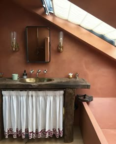 a bathroom with a sink, mirror and bathtub under a slanted skylight