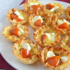 small appetizers on a plate with cheese and tomato toppings, ready to be eaten