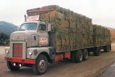 an old truck with hay bales on the back