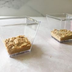 two square containers with food in them sitting on a counter top next to each other