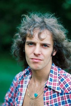 a close up of a person wearing a plaid shirt with long hair and piercings