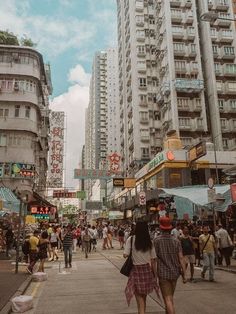 many people are walking down the street near tall buildings