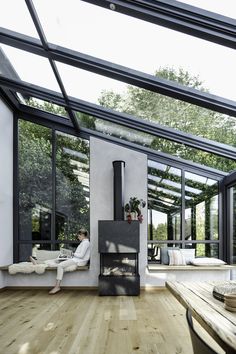 a person sitting on a couch in front of a fireplace with glass walls and floor to ceiling windows