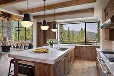 a large kitchen with wooden cabinets and an island in front of a window that overlooks the mountains