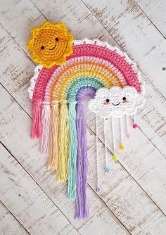 a crocheted rainbow and cloud decoration on a white wood floor with a wooden background