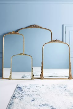 three mirrors sitting next to each other on top of a white rug in front of a blue wall